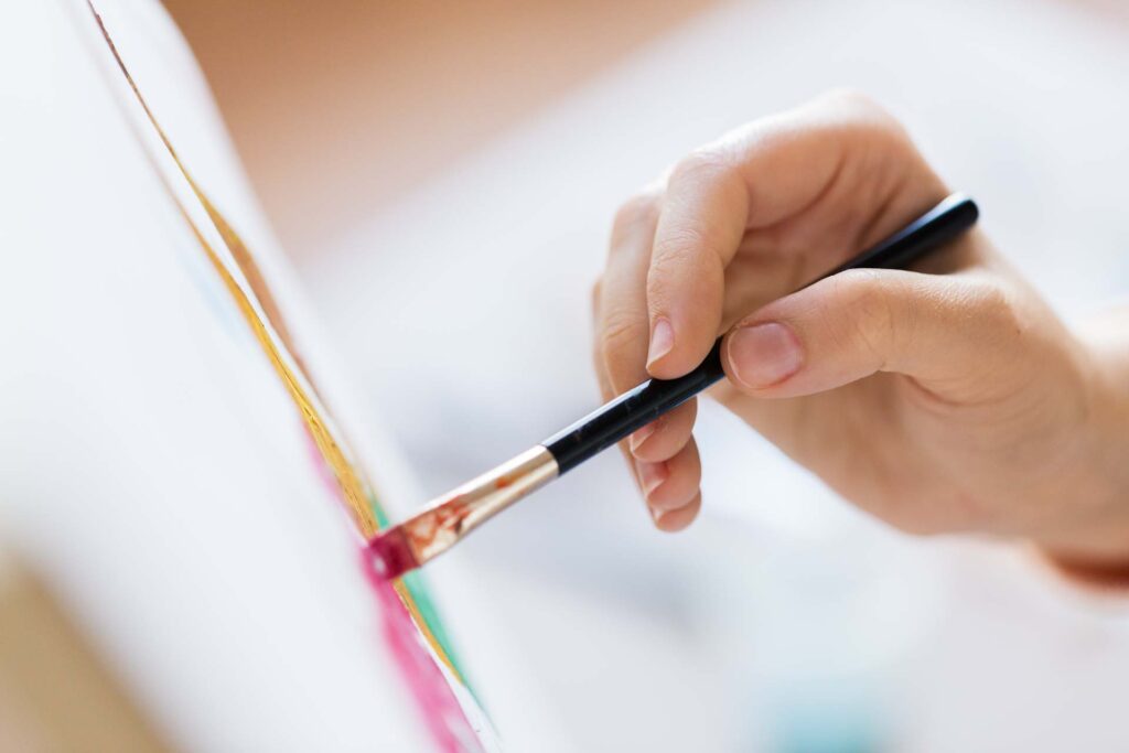 Hand holding a paintbrush to canvas illustrates the Need step of Monroe’s Motivated Sequence five-step process in persuasive speech, developing the problem and motivating audience desire for change.