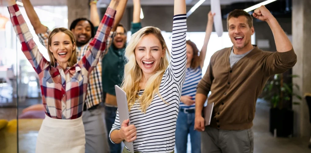 An in person team showing enthusiasm after performing various team building activities and team building exercises.